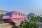 A pink Sentosa Island monorail tram outside a train station