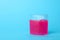 Pink slime in plastic container on blue background. Space for text