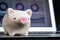 Pink smiling piggy bank on laptop displaying online financial chart and graph using as online stock trading, asset allocation or