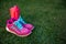 Pink sneakers with blue cord and pink water battle at the fresh green grass background