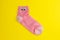 pink sock with googly eyes isolated on yellow background