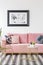 Pink sofa decorated with pillows, poster on the wall and golden