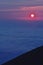 The pink solar disk seen from high altitude at sunrise. alpine sea at the mountain