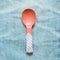 Pink spoon on blue jeans background