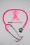 Pink stethophonendoscope, satin ribbon and scalpel on white background.