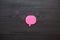 Pink sticker on black wooden background. A piece of paper to write down ideas. Sticker in the form of a speech cloud