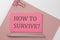 Pink sticker on pink paper with pencil on a white background with text HOW TO SURVIVE