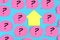 Pink stickers with question marks drawn on them on a blue background. In the center there is an empty yellow sticky