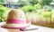 Pink Straw farmer hat with smart phone on table with garden background.