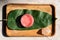 Pink strawberry scrub or cream and green leaves on wooden background. Skin care beauty and spa concept