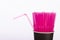 Pink straws in black paper cup on white background. One flexible straw apart
