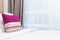 Pink stripe pillow on white bed in a brightly lit bedroom