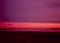 A Pink Sunrise and Purple Sky Over A Red Beach