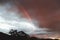 Pink sunrise with rainbow in front of the colorful clouds with mountain tops and eucalyptus gum trees