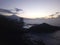 Pink sunset on the ocean. Black volcanic rocks, stones, houses, water. Nice sky with clouds