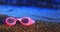 Pink swimming glasses on the sand with the red hearts on the len