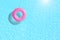 Pink swimming pool ring float in blue water.