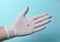 Pink tablet on medic hand with white latex gloves on a blue background. Medical concept.