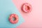 Pink tasty donuts decorated with colorful sprinkles on blue and pink background. Sweet donuts minimal flat lay