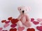 Pink teddy bear surrounded by pink and red hearts on a white background