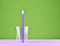 Pink toothbrush in a transparent cup on a minty green pastel background, minimalist trend.