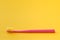 Pink toothbrush on yellow background for oral hygiene to clean teeth, gums and tongue