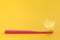 Pink toothbrush on yellow background for oral hygiene to clean teeth, gums and tongue