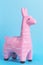 Pink toy lama figure on blue background