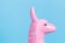 Pink toy lama head on blue background