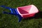 Pink toy wheelbarrow on green grass