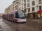 Pink tram on the street of Riga on a wet January day after rain with snow.