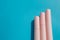 Pink tubes of cosmetics on a blue background. Closed tubes of lipstick, liquid lip gloss, mascara, eyeliner