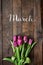 Pink, tulips bunch on dark barn wood planks background. March text, copy, lettering. Vertical postcard template.