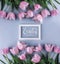 Pink tulips flowers on blue background with frame for text. Waiting for spring. Happy Easter card. Flat lay, top view