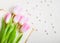 Pink tulips with heart and beads over white wooden table. Closeup