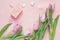 Pink tulips, hearts and gift box on rosy background. Top view wi