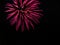 Pink twirling streams of fireworks light up black sky