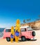 Pink Vintage, Retro, Old-fashioned mini bus van camper VW T2 with surfboard on beach, cliff, palm tree