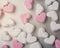 Pink and white heart-shaped marshmallows evenly laid out on gray aluminum background