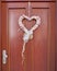 Pink white heart shaped wreath on solid wood house door