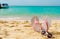 Pink and white sandals, sunglasses on sand beach at seaside. Casual fashion style flipflop and glasses at seashore. Summer