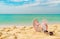 Pink and white sandals, sunglasses on sand beach at seaside. Casual fashion style flipflop and glasses. Summer vacation