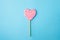 A pink and white spiral heart lollipop on blue background, flat lay minimal concept, trendy pop art style photo, .