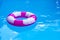 Pink-white swimming pool ring, float in refreshing blue water. Sunny day at resort.