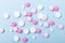 Pink and white tablets on blue background Heap of assorted various medicine tablets