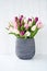Pink and white tulips bouquet in gray vase.