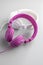 Pink and white wired stereo headphones on gray background