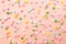 Pink,  white, yellow, blue and green star shaped sprinkles on light pink background. Colourful edible cake decoration on pink