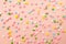 Pink,  white, yellow, blue and green star shaped sprinkles on light pink background. Colourful edible cake decoration on pink