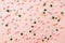 Pink,  white, yellow, blue and green star shaped sprinkles on light pink background. Colourful edible cake decoration on pink